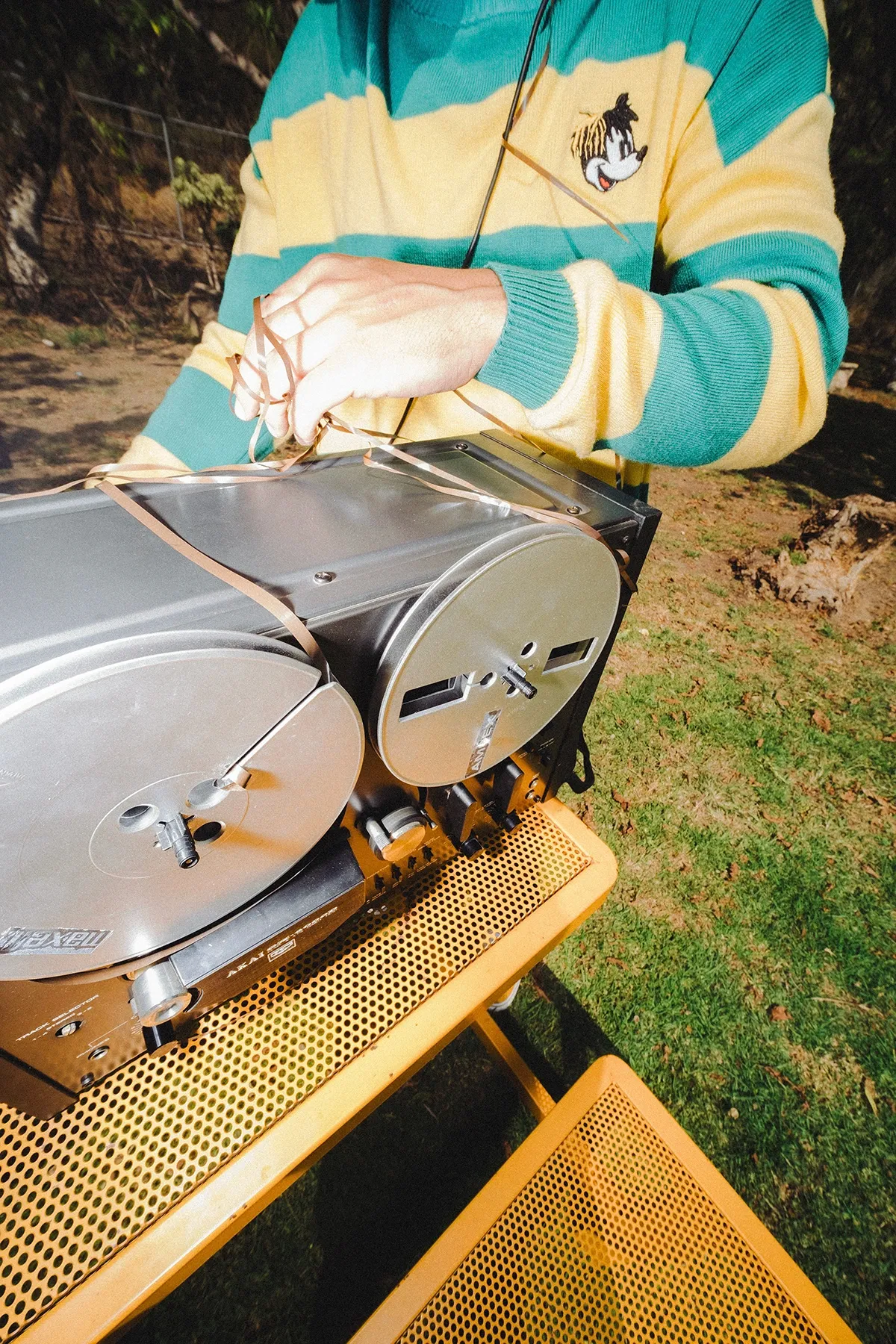 Detalle de las manos de Galo Barker ajustando una grabadora de carrete al aire libre