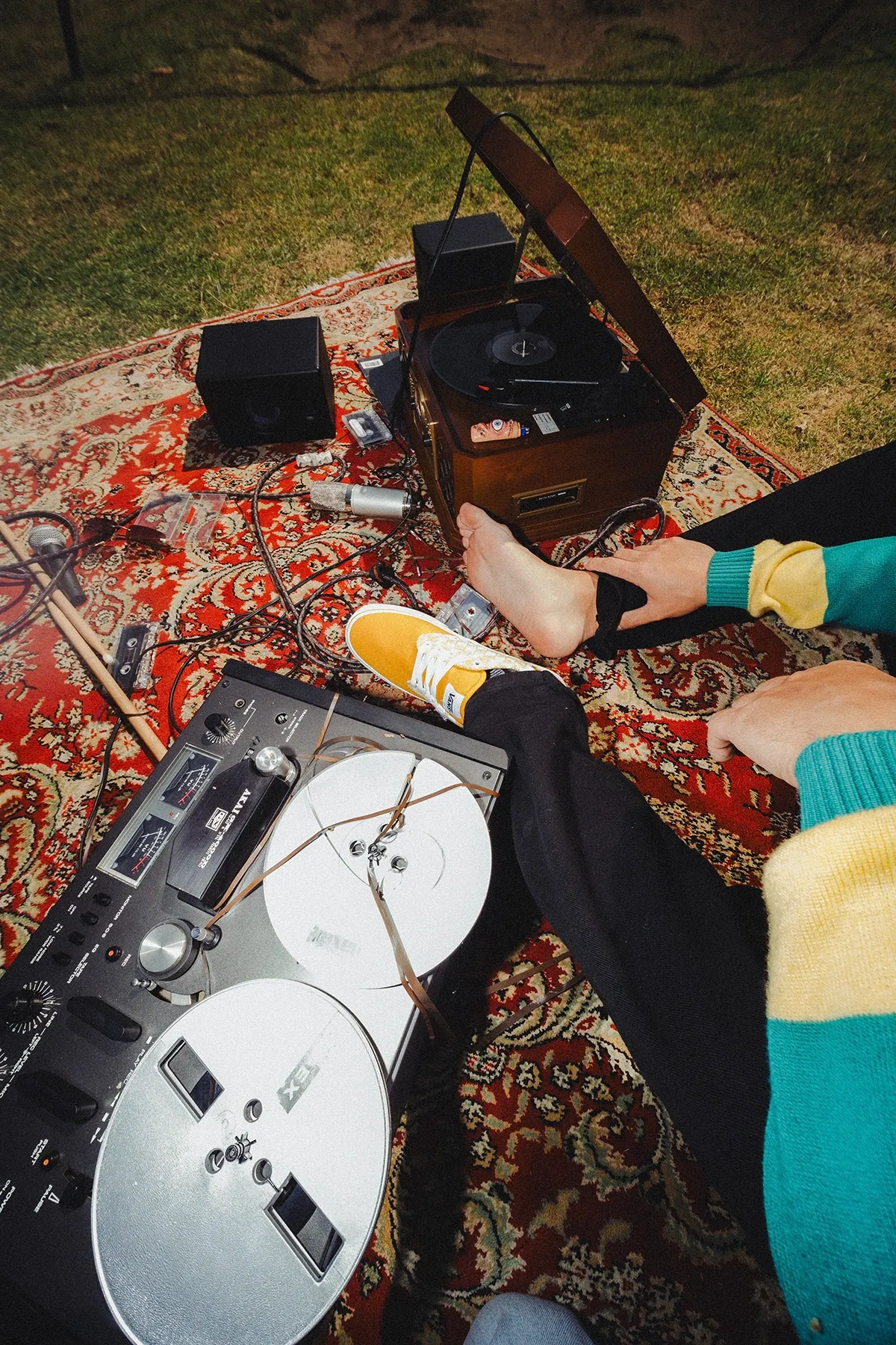 Grabadora de carrete y tocadiscos sobre un tapete en el pasto junto al pie descalzo de Galo Barker